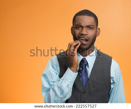 Toothache. Portrait sad young man, worker touching face having bad pain, tooth ache, isolated orange background. Negative human emotions, facial expressions, feelings, reaction, dental health, care