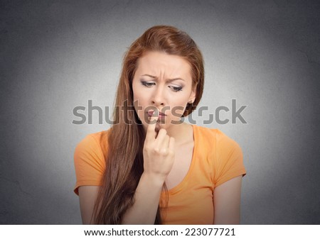 Portrait puzzled woman thinking worried finger on lips gesture looking down isolated grey wall background. Human face expressions, emotions, feelings, body language, perception