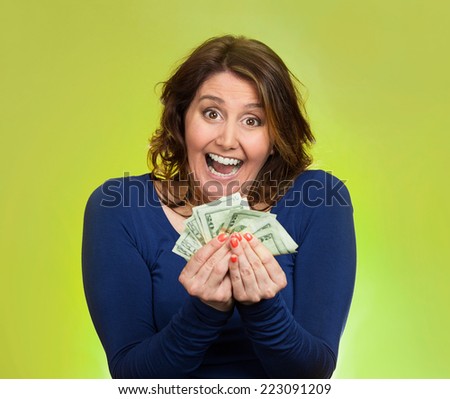 Closeup portrait super happy excited successful middle aged business woman holding money dollar bills in hand isolated green background. Positive emotion facial expression feeling. Financial reward