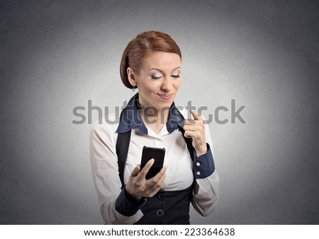 Closeup portrait angry young business woman annoyed worker pissed off employee while on mobile pointing with finger at smart phone isolated grey wall background. Negative emotion facial expression