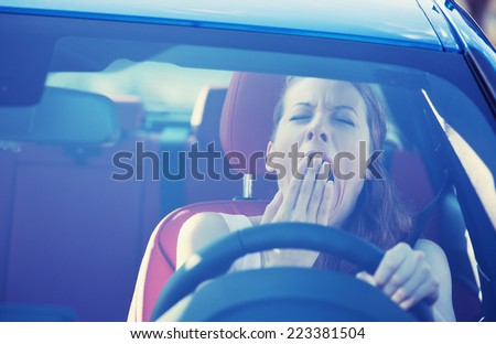Closeup portrait sleepy tired fatigued exhausted young attractive woman driving her car in street traffic after long hour trip windshield front view. Transportation sleep deprivation accident concept
