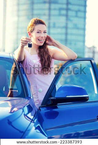 Portrait happy smiling young attractive woman buyer standing next to new blue car showing keys isolated outside dealer, dealership lot corporate office. Personal transportation auto purchase concept