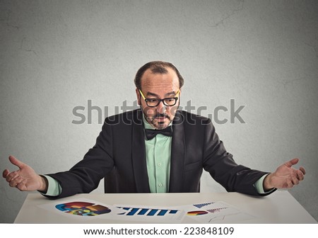 Stressed businessman executive sitting at table looking at financial report document with graph chart diagram unhappy with company result profit. Stock market, anticipation of financial crisis concept