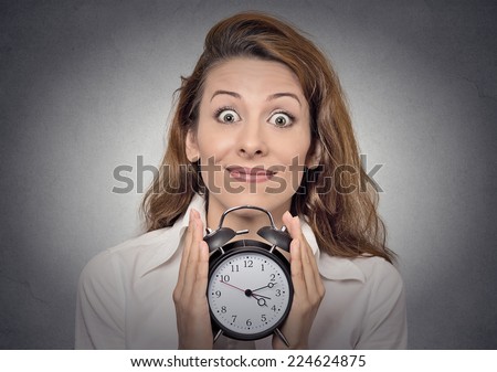anticipation. Headshot young funny looking excited business woman holding alarm clock waiting isolated grey wall background. Human face expressions, emotions. Time, punctuality, busy schedule concept