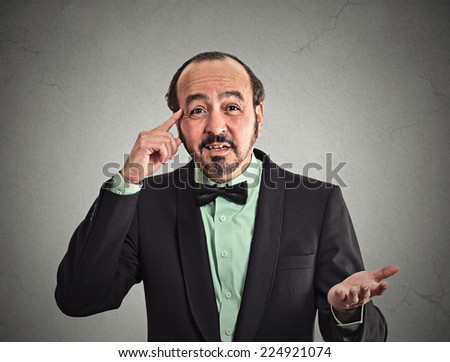Closeup portrait angry middle aged business man gesturing with his finger against his temple, asking are you crazy? isolated grey wall background. Negative human emotion face expression body language
