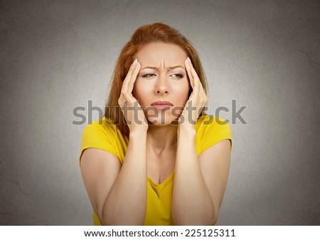 Young woman suffering from headache hands on head temples isolated on grey wall background. Human face expression emotion feeling