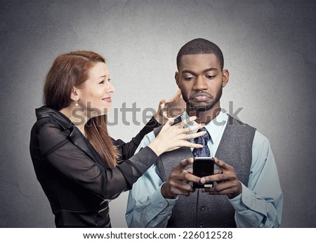 Obsessed with phone work. Attractive woman angry with handsome man who ignores her looking at smart phone reading texting isolated grey wall background. Phone addiction mania concept. Face expression