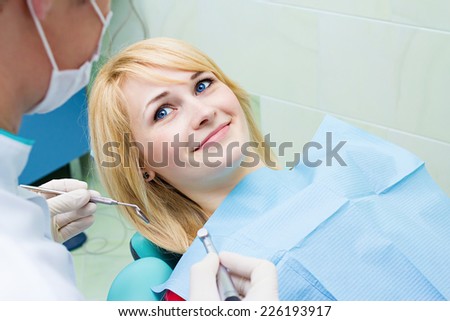 Closeup portrait smiling happy patient in dentist office, doctor holding angled mirror ready to examine teeth oral cavity. Clinic visit, preventive medicine annual check up. Positive facial expression