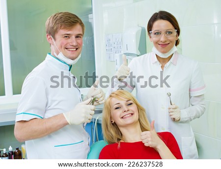 Portrait happy female health care professional dentist assistant satisfied smiling woman patient in office giving thumbs up sign gesture. Successful treatment procedure care outcome. Positive emotion