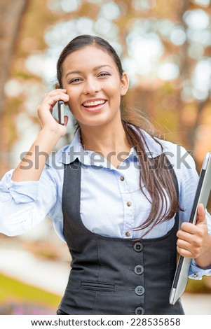 Portrait young woman, attractive businesswoman talking on cell phone having pleasant conversation receiving good news walking in park isolated outdoors autumn tree background. Positive face expression