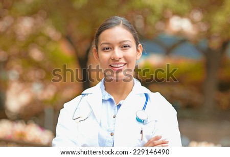 Closeup portrait young smiling confident female doctor healthcare professional isolated outside indian fall trees background. Patient clinic visit health care reform. Positive emotion face expression