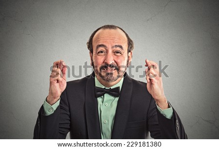Closeup portrait middle aged funny guy business man crossing fingers wishing hoping for best miracle isolated black grey wall background. Positive human emotion facial expression feeling attitude