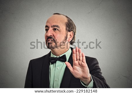 Closeup portrait middle aged handsome grumpy man with bad attitude giving talk to hand gesture with palm outward isolated grey background. Negative emotions, facial expression feelings, body language