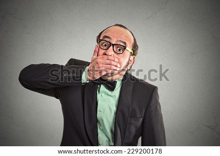 Shut up mouth, keep corporate deals secret. Portrait man worker employee covering his mouth. Speak no evil concept isolated grey background. Human emotion face expression feeling sign body language