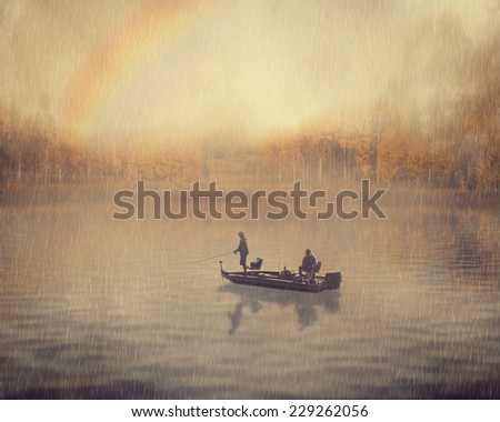 Retro style landscape image man and old guy fishing in a boat on a rainy foggy day with rainbow and fall autumn forest background. Peaceful nature leisure vacation hobby activity lifestyle concept