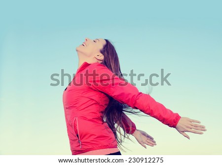 Woman smiling arms raised looking at blue sky taking deep breath celebrating freedom. Positive human emotion face expression feeling life perception success peace mind concept. Free girl enjoy nature