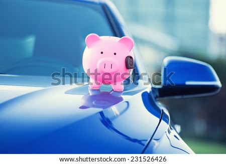 Closeup image new car with piggy bank, key on hood isolated outside corporate building. Dealership offering credit line finance services. Lease automobile purchase financing concept. Financial success