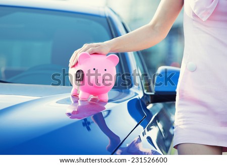 Cropped image woman customer, agent and new car, pink piggy bank key on hood isolated outside outdoors. Dealership offering credit line, finance services. Lease, automobile purchase, financing concept
