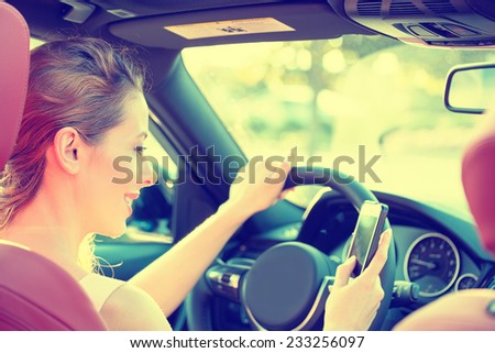 Young beautiful businesswoman sending a text message using mobile phone while driving car to work. Risky, reckless driver bad habits. Traffic safety rule violation lack of attention concept