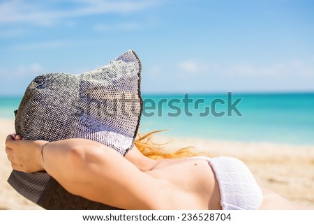 Young woman with sun hat enjoying the sea view sitting laying on a beach\'s chair close to the sea blue ocean. Travel tropical vacation paradise destination nature getaway freedom concept