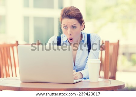 Shocked young business woman using laptop looking at computer screen blown away in stupor sitting outside corporate office. Human face expression, emotion, feeling, perception, body language, reaction