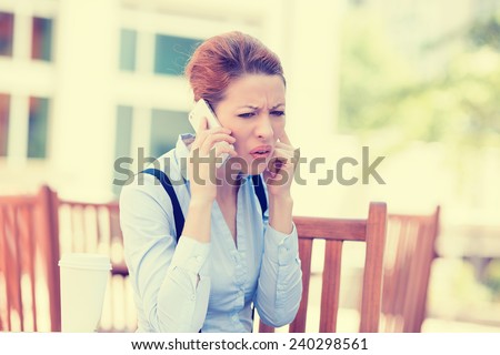 Closeup portrait upset sad skeptical unhappy serious woman talking on phone sitting outside isolated corporate office background. Negative human emotion face expression feeling life reaction. Bad news