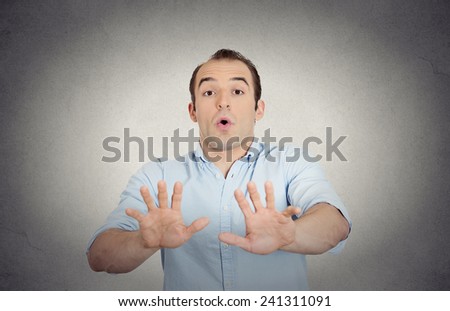 Closeup portrait helpless scared young man raising hand up to say no stop right there isolated grey wall background. Negative emotion facial expression feelings, signs symbols, body language, reaction