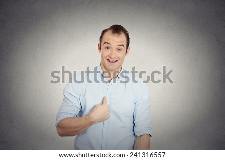 Closeup portrait smiling, happy, surprised, young business man, funny looking guy asking question, you talking to me, you mean me? Isolated grey wall background. Human emotions, facial expressions