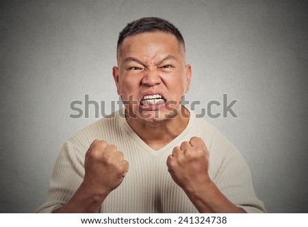 Closeup portrait headshot angry middle aged man with open mouth fist up in air aggressive screaming isolated grey wall background. Negative human emotion face expression feeling body language reaction