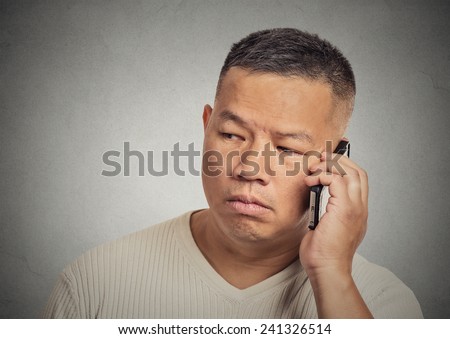 Closeup portrait headshot upset, sad, depressed, worried young man employee father worker talking on mobile phone isolated grey wall background. Human face expressions, emotions, feelings, reactions