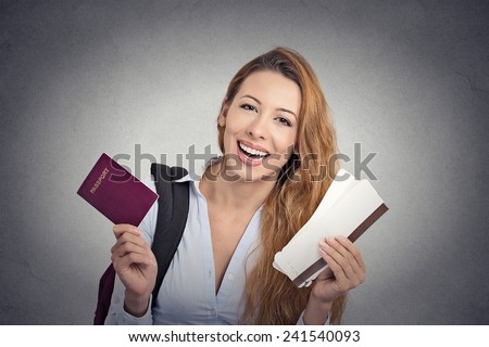 Portrait happy tourist young woman holding passport holiday flight ticket standing isolated on grey wall background. Positive human emotions face expression. Travel vacation getaway trip concept