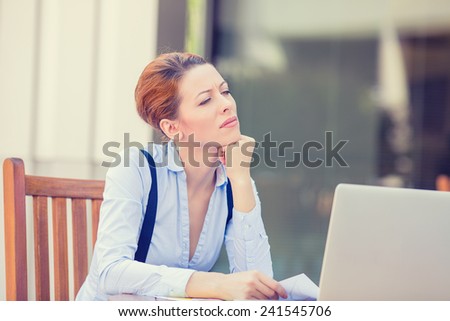 Portrait young stressed displeased worried business woman sitting in front of laptop computer isolated outdoors city office background. Negative face expression emotion feelings problem perception