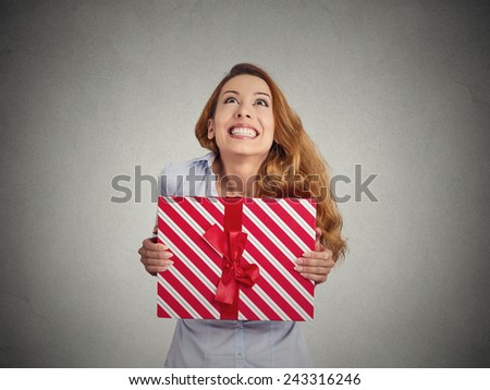 Gift box in hands of young happy woman isolated on grey wall background. Positive emotions face expressions feelings perception