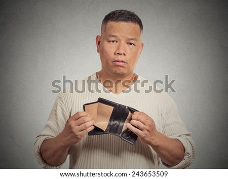 Closeup portrait stressed, upset, sad, unhappy middle aged  man standing with, holding empty wallet isolated grey wall background. Financial difficulties, bad economy concept. Negative emotion