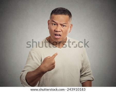 Closeup portrait, angry, unhappy, annoyed young man, getting mad, asking question you talking to, mean me? Isolated grey wall background. Negative human emotion, facial expressions, feelings, reaction