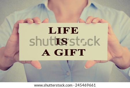 woman hands holding white card with life is a gift message text note isolated on grey wall office background