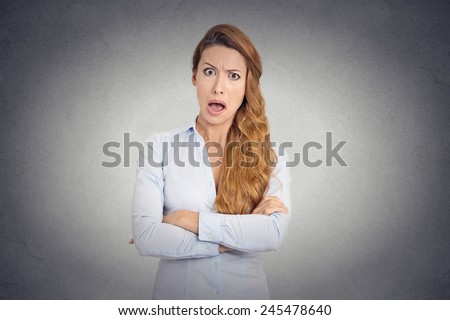 Pissed of angry young woman with disgusted face expression shouting on grey wall background