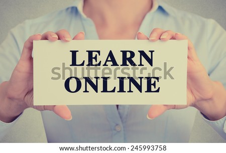 Closeup businesswoman hands holding white card sign with learn online text message isolated on grey wall office background. Retro instagram style image. Globalization education technology concept