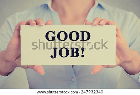 Businesswoman hands holding white card sign with good job text message isolated on grey wall office background. Retro instagram style image