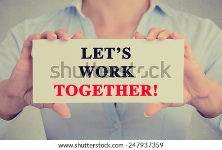Businesswoman hands holding white card sign with let\'s work together text message isolated on grey wall office background. Retro instagram style image