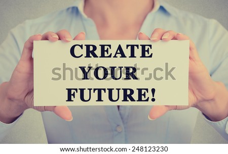 Businesswoman hands holding white card sign with create your future text message isolated on grey wall office background. Retro instagram style image