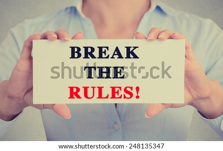 Closeup businesswoman hands holding white card sign with break the rules text message isolated on grey wall office background. Retro instagram style image