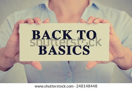 Closeup businesswoman hands holding white card sign note with back to basics text message isolated on grey wall office background. Retro instagram style image