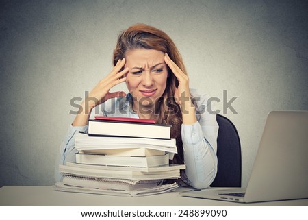 Too much work tired stressed young woman sitting at her desk with books in front laptop computer isolated grey wall office background. Busy college schedule burnout workplace sleep deprivation concept
