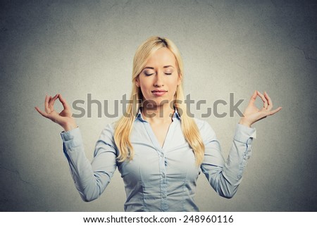 Portrait happy young business woman in blue shirt eyes closed hands raised in air relaxing meditating taking deep breath isolated grey wall background. Corporate life style. Stress relief technique