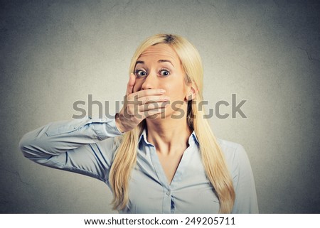 Woman forced to cover her mouth with hand isolated on grey wall background. Fright scared face expression. Human emotion perception reaction. Freedom of speech violation concept. Gender inequality