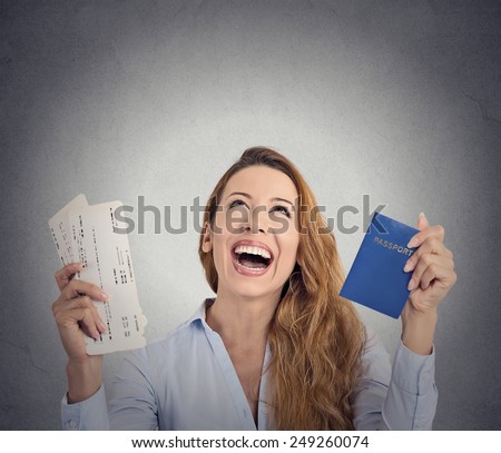 Portrait happy excited tourist young woman holding passport holiday flight ticket looking up isolated grey wall background. Positive human emotion face expression. Travel vacation getaway trip concept