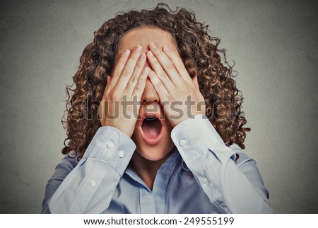Headshot young scared woman covering eyes wide open mouth isolated on grey wall background. Human emotions face expressions feelings reaction perception gesture