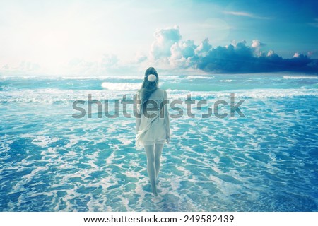 Young woman walking on a dreamy beach enjoying ocean colorful blue sky view. Landscape nature screen saver