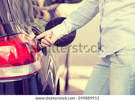 Woman opening car gas tank cap at petrol station